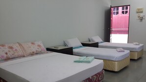 A hotel room with three beds, a nightstand, and a door with a pink frame. - Budget Beach Resort (Pangkor Island)
