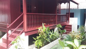 A red wooden building with a balcony, steps, and potted plants. - Budget Beach Resort (Pangkor Island)