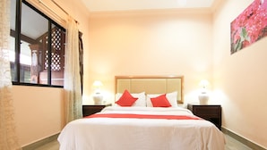 A neatly arranged hotel room with a large bed, two bedside tables with lamps, and a window with curtains. - Hotel O Ombak Inn Chalet (Pangkor Island)