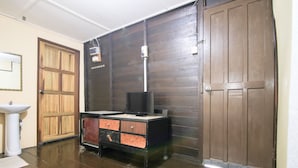 A room with a wooden wardrobe, a desk with a computer and a television, and a white pedestal sink. - Hotel O Ombak Inn Chalet (Pangkor Island)