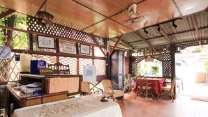 A restaurant with a covered outdoor seating area, wooden furniture, and a table with a white tablecloth. - Hotel O Ombak Inn Chalet (Pangkor Island)