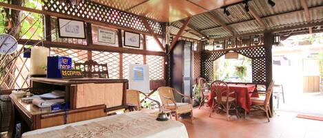 A restaurant with a covered outdoor seating area, wooden furniture, and a table with a white tablecloth.