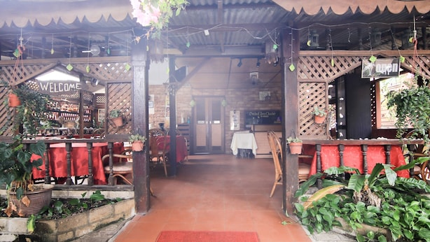 A restaurant with a 'WELCOME' mat at the entrance, wooden furniture, and potted plants. - Hotel O Ombak Inn Chalet (Pangkor Island)