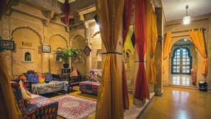Une pièce de style traditionnel, avec des murs richement décorés, une grande fenêtre et un ensemble de meubles comprenant un canapé.