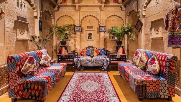 Une pièce de style traditionnel, dotée d’une architecture richement décorée, d’un ensemble de canapés disposés au centre et de deux canapés placés de part et d’autre.