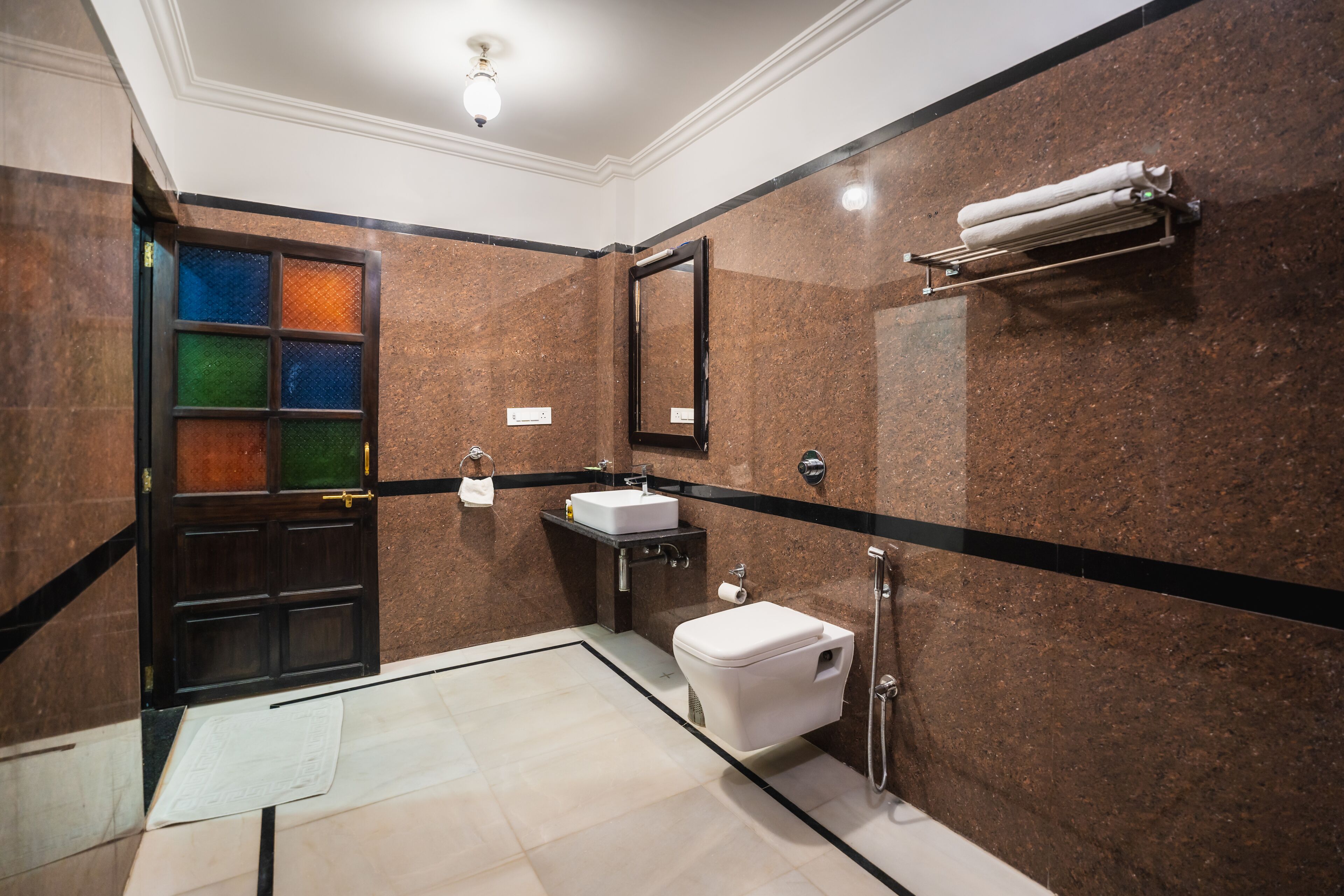 Un baño con pared de mármol, un lavabo, un inodoro y un perchero para toallas.
