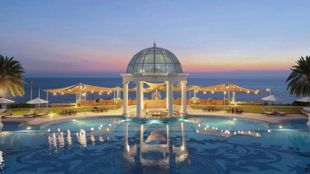 A pool area with a gazebo, lounge chairs, and umbrellas.