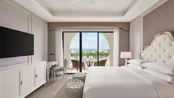 Habitación de hotel con una cama grande, televisión de pantalla plana, escritorio y balcón con vistas a la ciudad.