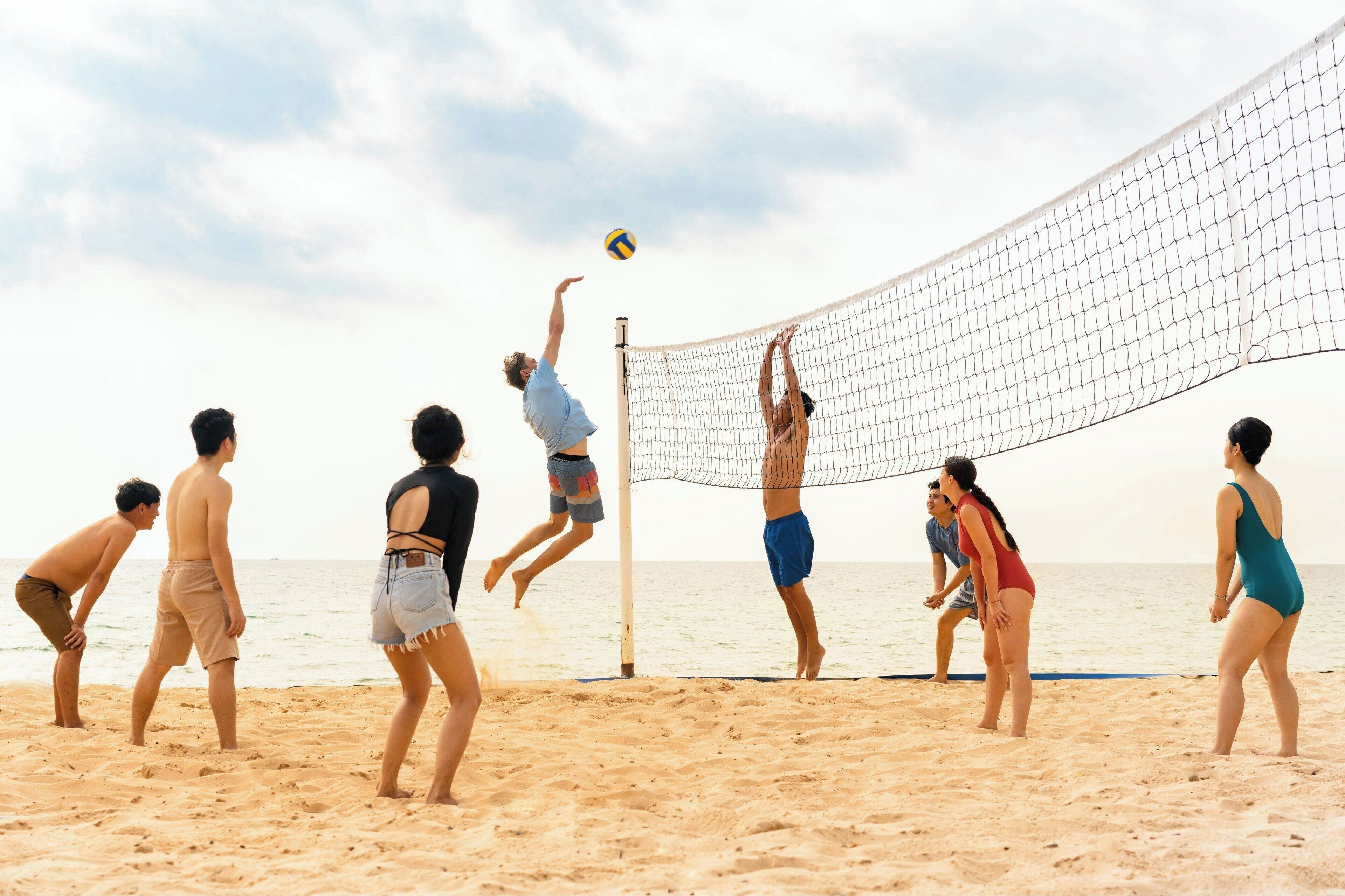 Un grupo de personas jugando voleibol de playa en una arena con cielo despejado.