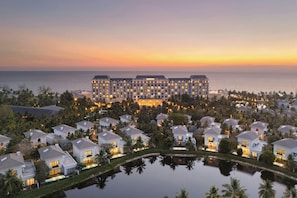 A resort with a large building, multiple guest houses, and a body of water.