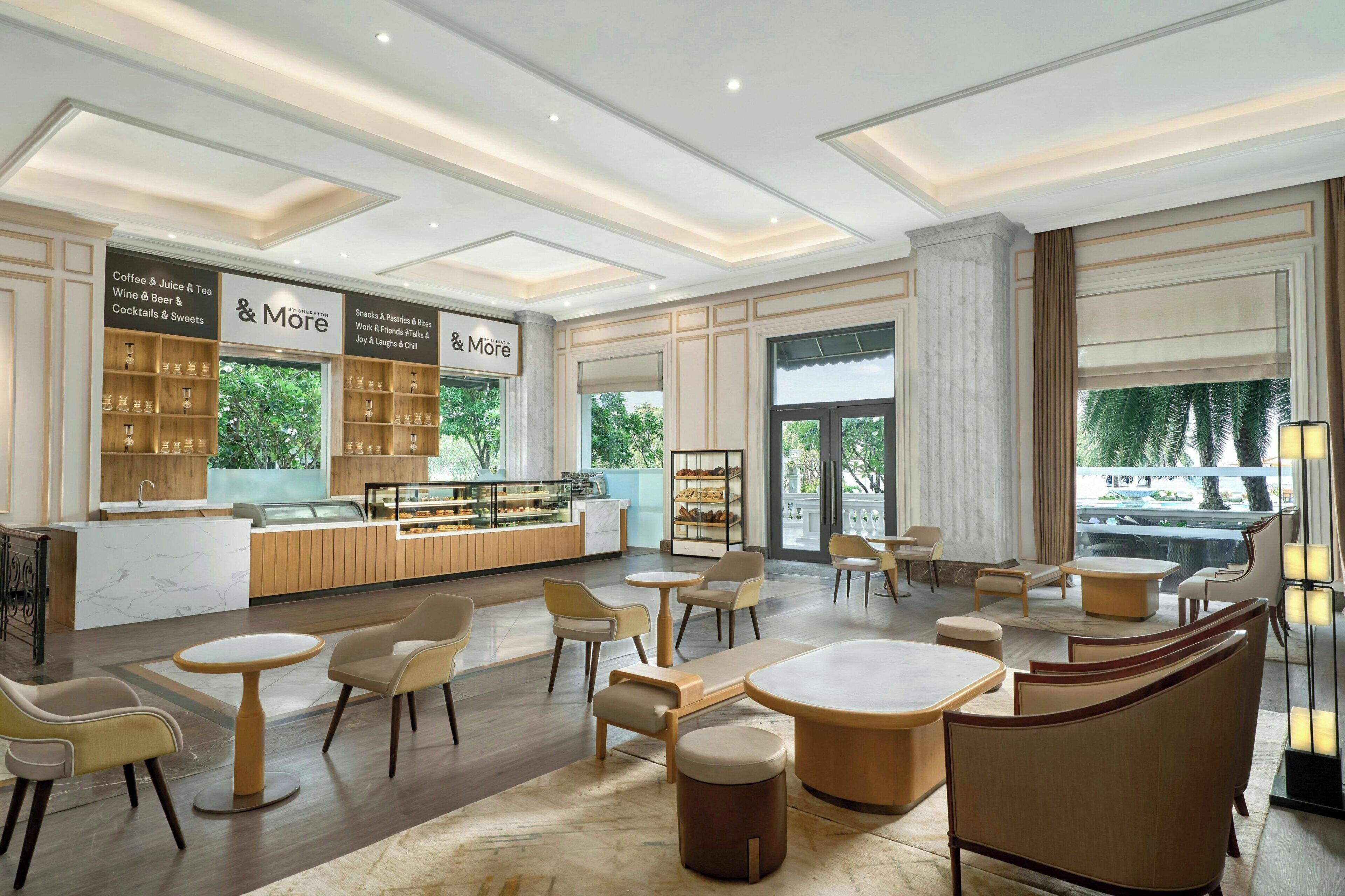 A modern cafe with a bar area, seating, and a view of greenery outside.