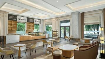 A modern cafe with a bar area, seating, and a view of greenery outside.
