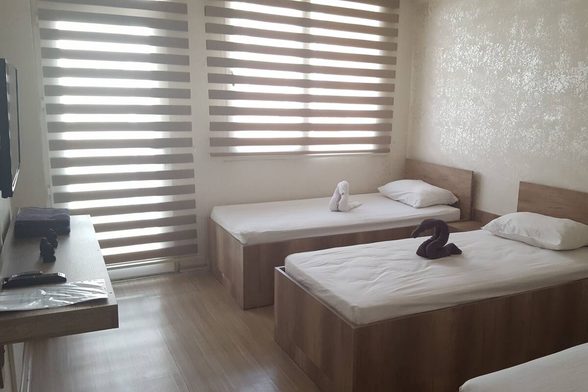 Una habitación de hotel con dos camas individuales, un escritorio de madera y una ventana con persianas.