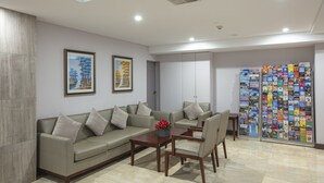 A modern lobby with a sofa set, a coffee table, and a wall of travel brochures. - Megaboom City Hotel (Sydney)