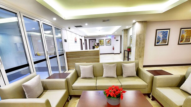 A modern lobby with a sofa set, a coffee table, and a reception desk. - Megaboom City Hotel (Sydney)