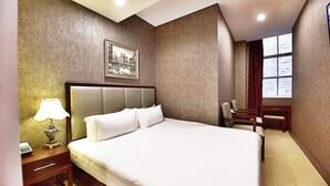 A hotel room with a large bed, a nightstand with a lamp, a desk, and a chair. - Megaboom City Hotel (Sydney)