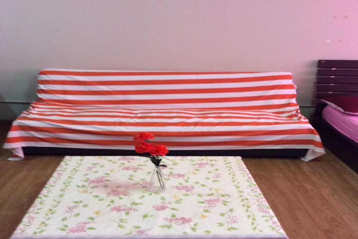 A bed with striped bedding and a floral table runner.