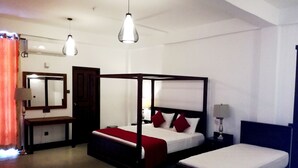 A modern hotel room with a four-poster bed, a smaller single bed, a bedside table with a lamp, a mirror, and a wardrobe. - Hasara Guest House (Galle)