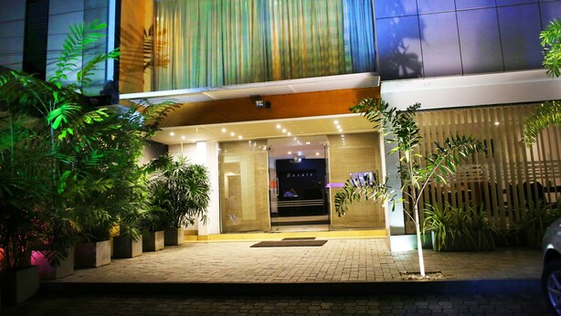 A modern hotel entrance with a glass door, potted plants, and a brick pathway. - Hasara Guest House (Galle)
