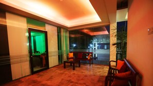 A lobby with a reception desk, seating area, and a glass door leading to a room. - Hasara Guest House (Galle)