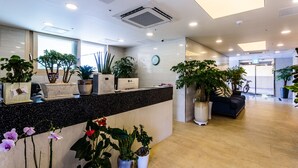 Een moderne receptie met een zwarte toonbank, potplanten, een klok en een zithoek met een bank en een fiets.