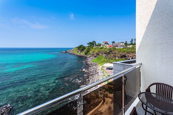 A balcony with a view of a rocky coastline and turquoise sea. - Seastay Hotel & Spa (Jeju City)