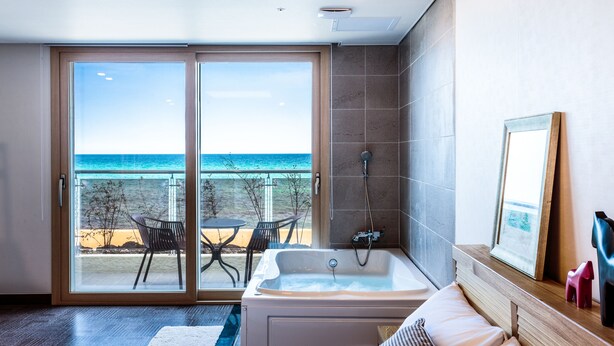 Een hotelkamer met een grote schuifglazen deur die leidt naar een balkon met uitzicht op de oceaan.