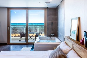 A hotel room with a large sliding glass door leading to a balcony with a view of the ocean. - Seastay Hotel & Spa (Jeju City)