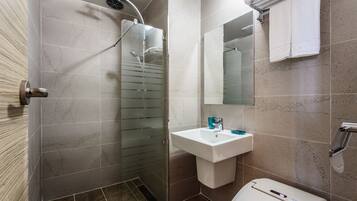 Un baño moderno con ducha acristalada, lavabo blanco y retrete.