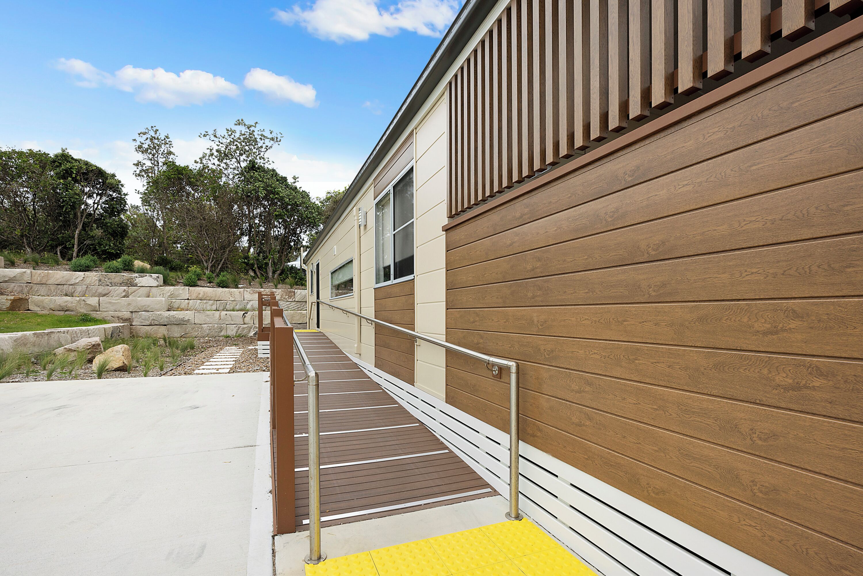 A modern building with a wooden exterior and a concrete pathway leading to a door.