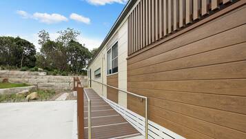 A modern building with a wooden exterior and a concrete pathway leading to a door.