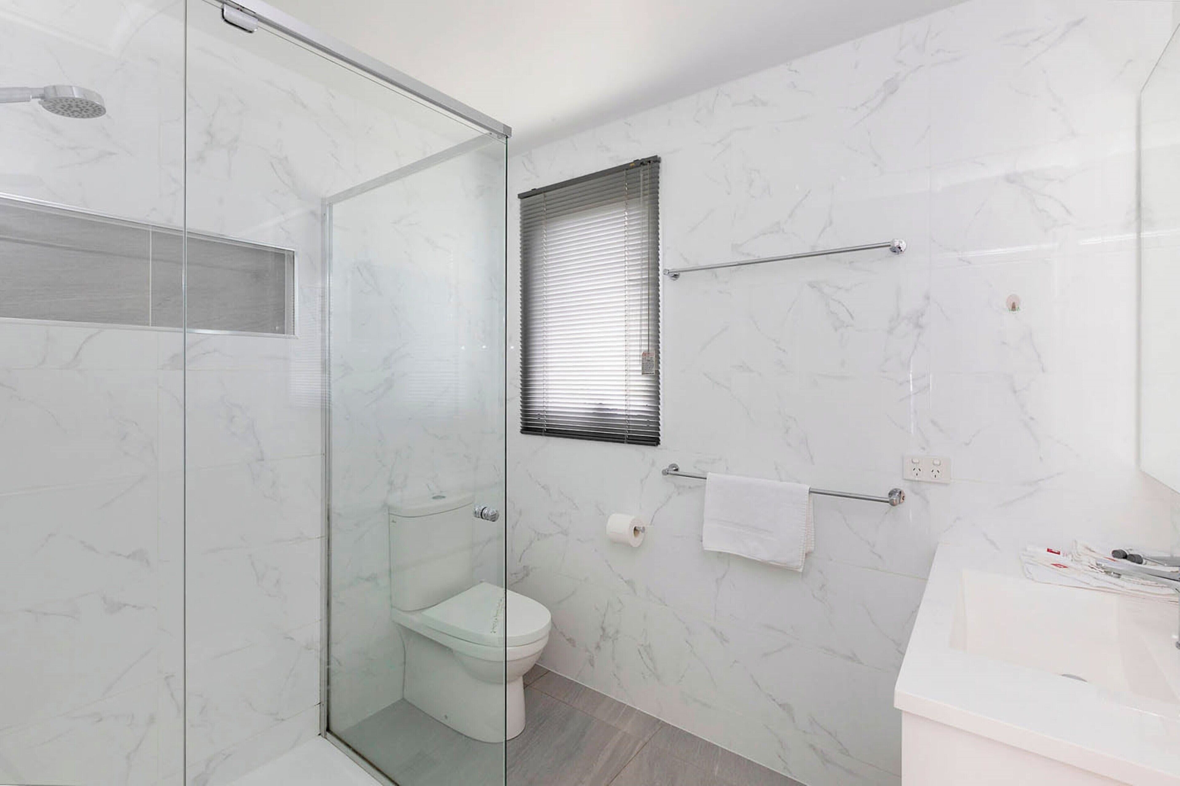 Un baño moderno con ducha de vidrio, inodoro y lavamanos.