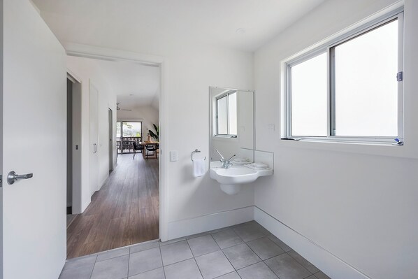 A modern bathroom with a large window, a sink, and a mirror.