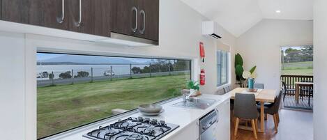 Una cocina moderna con un ventanal grande, una estufa a gas y un comedor con mesa y sillas.