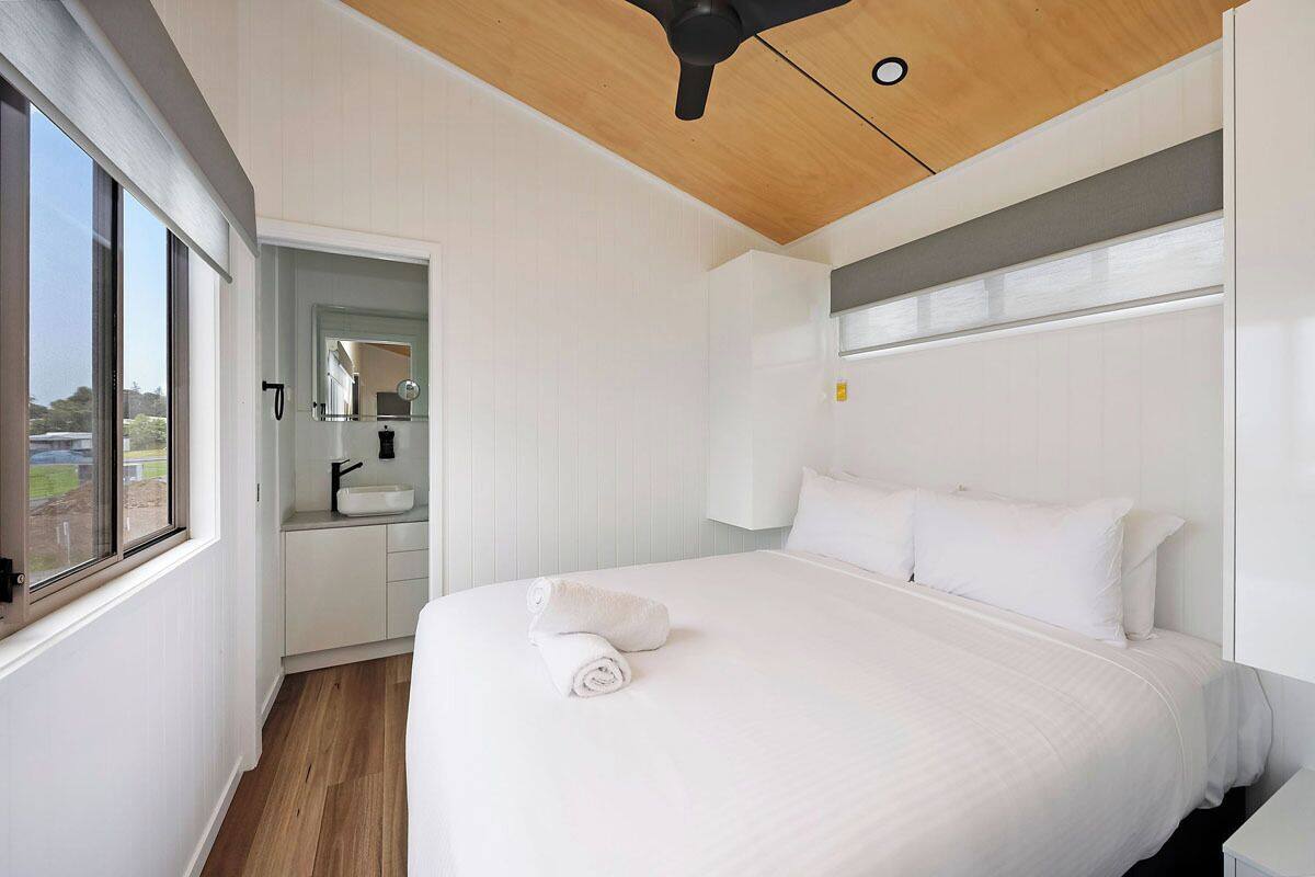 A modern hotel room with a large bed, a built-in sink, and a view of the outdoors.