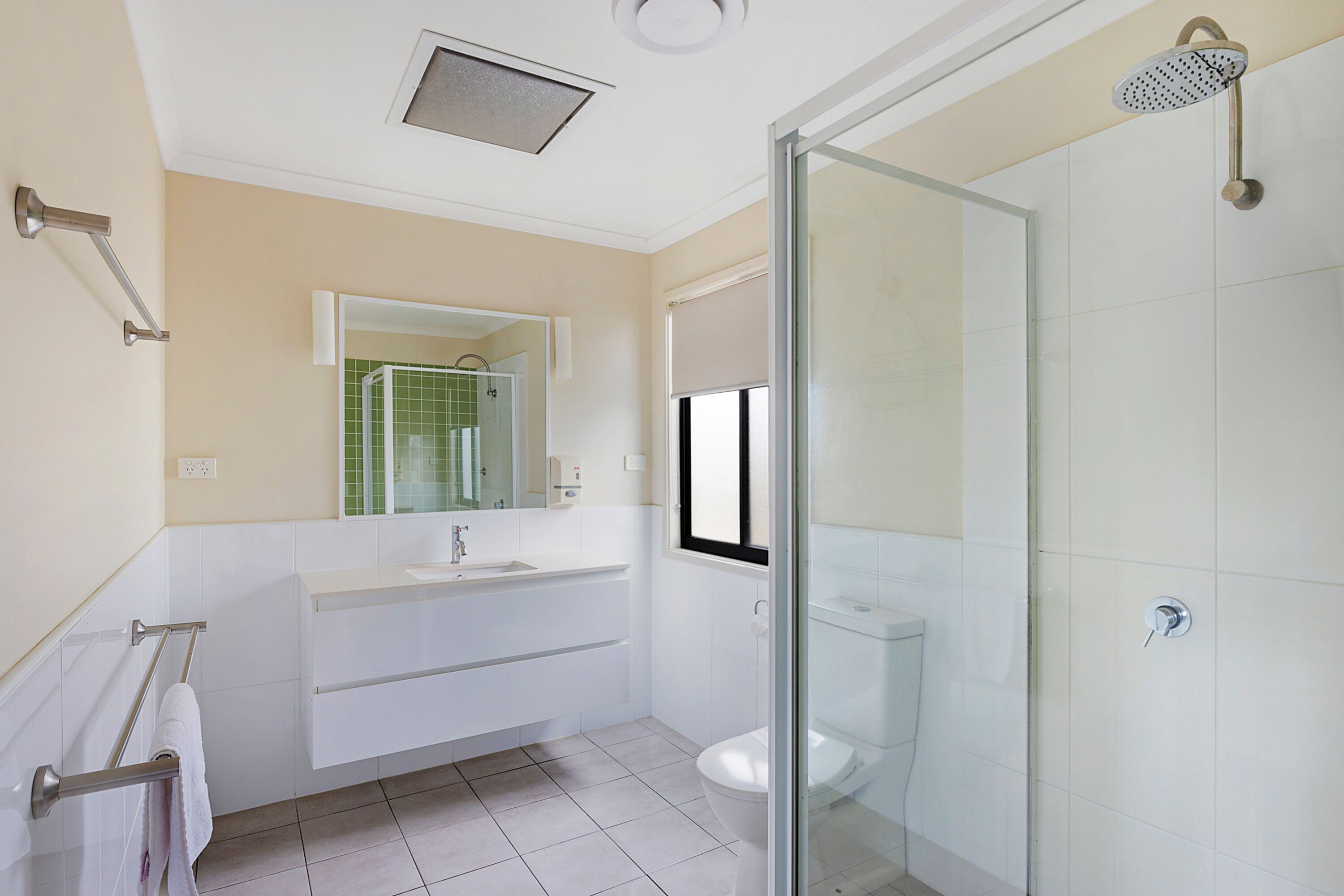 Un baño moderno con cabina de ducha de vidrio, un lavamanos blanco y un inodoro.