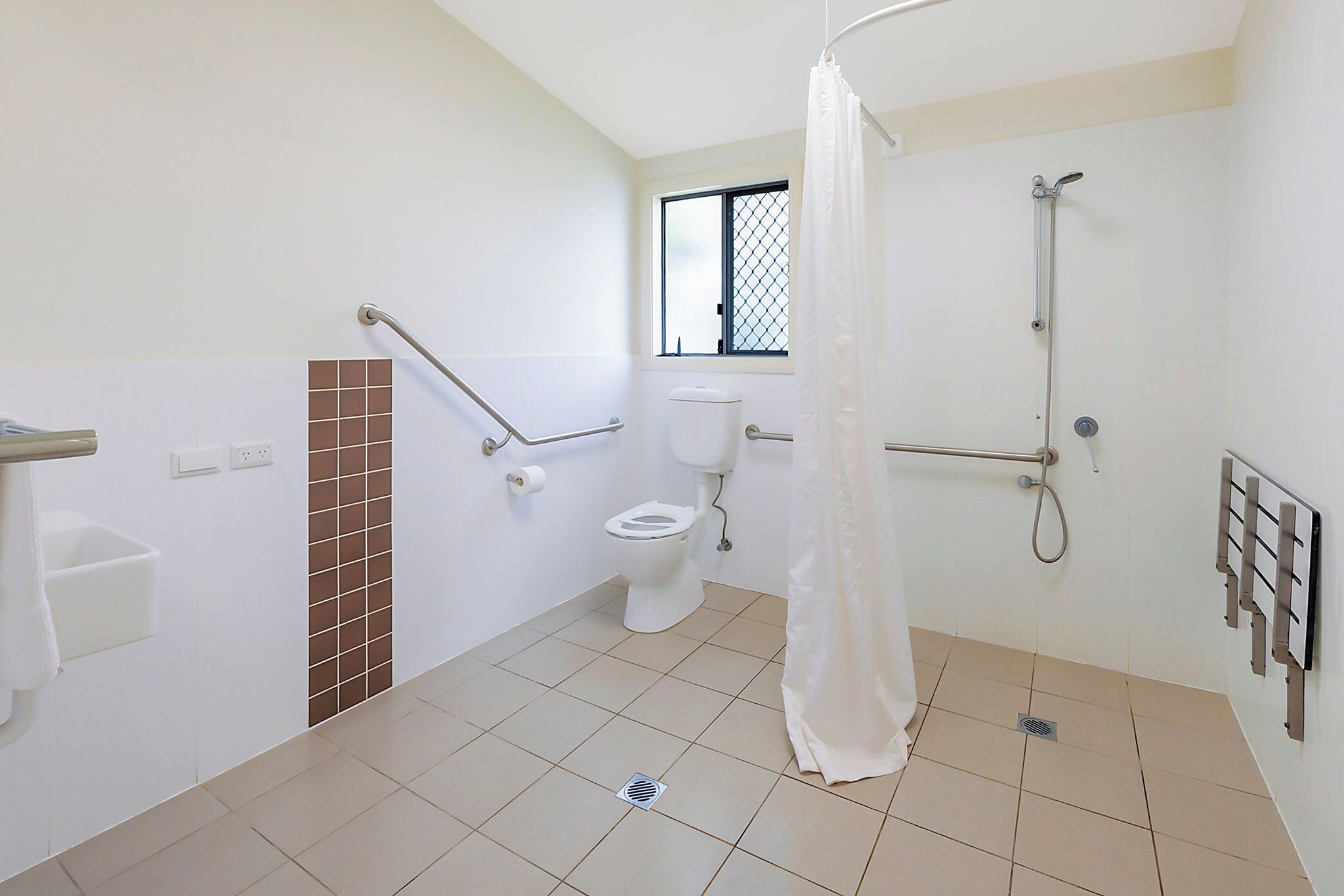 Ein Badezimmer mit Toilette, Dusche und Haltegriffen.