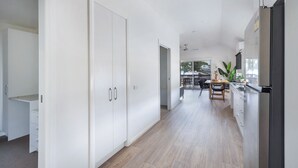 A modern kitchen with a refrigerator, a dining area with a table and chairs, and a hallway with a wardrobe. - Reflections Bermagui - Holiday Park (Bermagui)