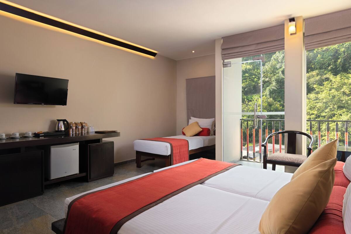 Une chambre d’hôtel comprenant un lit, un bureau avec une machine à café, une télévision et un balcon avec une chaise.