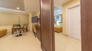 Una habitación de hotel moderna con escritorio, silla y televisor de pantalla plana montado en la pared.