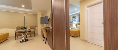 Una habitación de hotel moderna con escritorio, silla y televisor de pantalla plana montado en la pared.