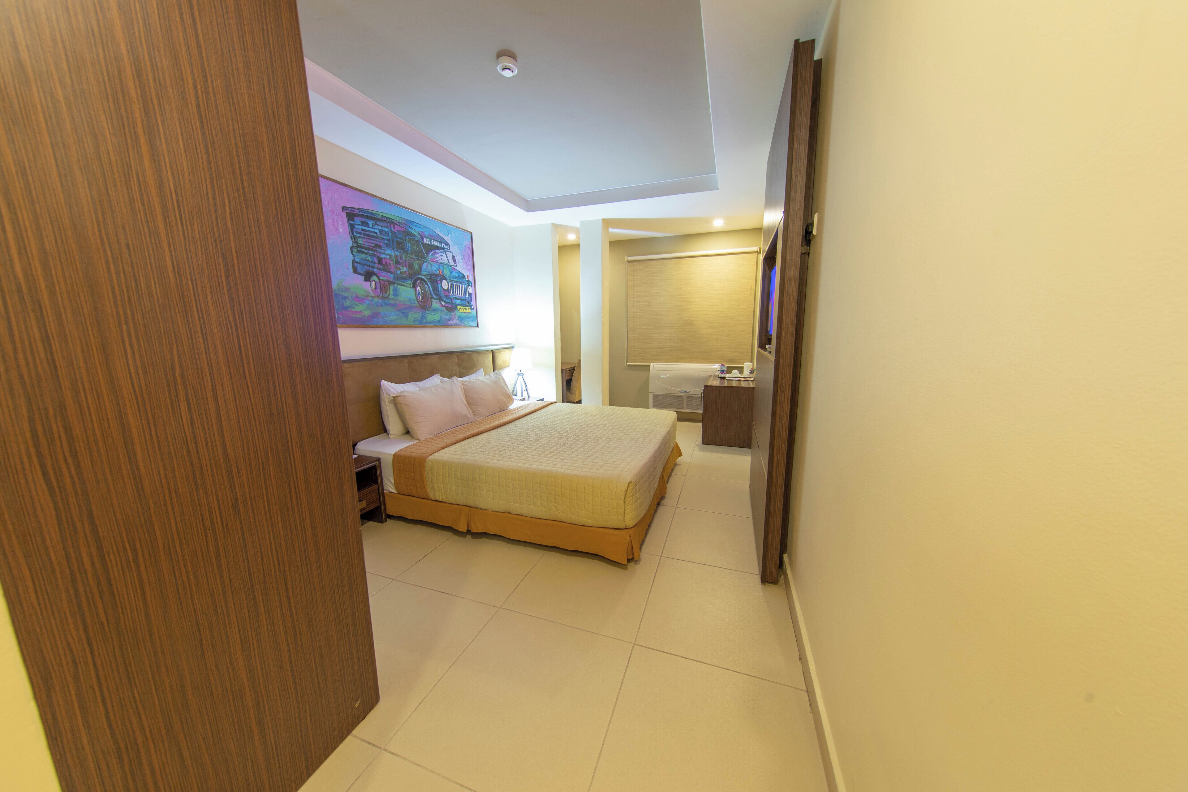 A hotel room with a large bed, a desk, a chair, and a bathroom.
