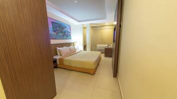 A hotel room with a large bed, a desk, a chair, and a bathroom.