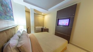 Una habitación de hotel moderna con una cama grande, un televisor de pantalla plana y un baño con toallero.