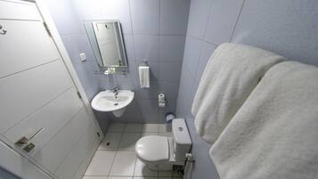 A bathroom with a toilet, sink, and mirror.