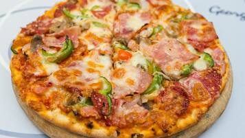 Une pizza garnie de divers ingrédients, présentée sur une planche en bois.