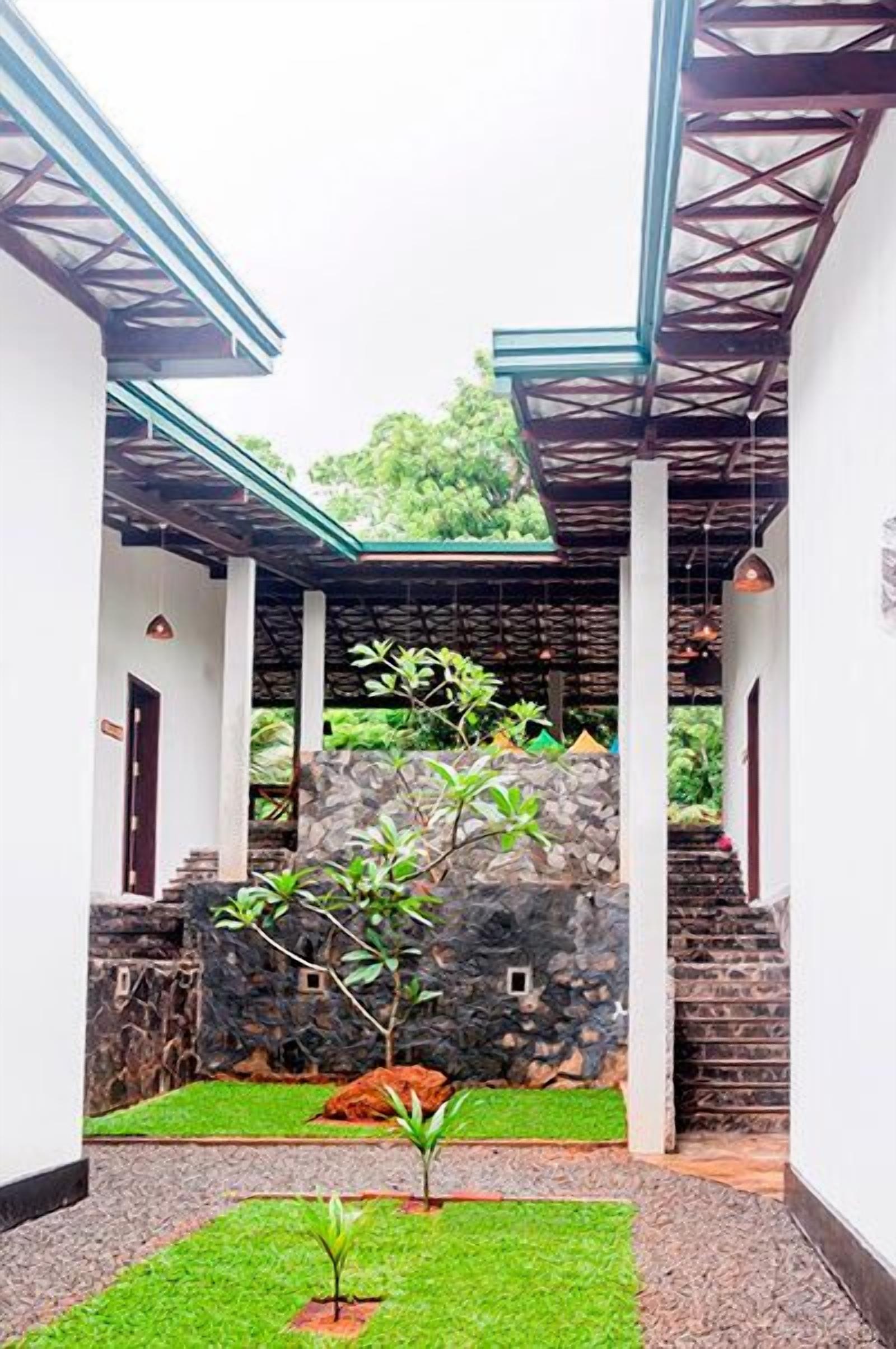 A courtyard with a stone wall, a small tree, and a staircase leading to a covered area.