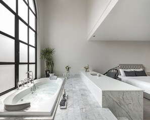 A modern bathroom with a large bathtub, a white vanity, and a bed with a headboard. - Hotel Once Bangkok (Bangkok)