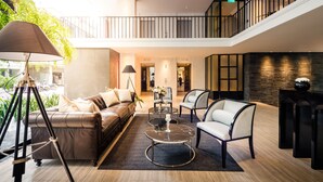 A spacious lobby with a leather sofa, two armchairs, a glass coffee table, and a tripod lamp. - Hotel Once Bangkok (Bangkok)