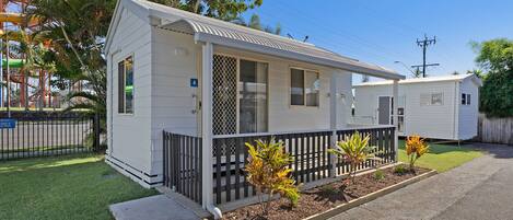 A single-story mobile home with a fenced front yard and small plants.